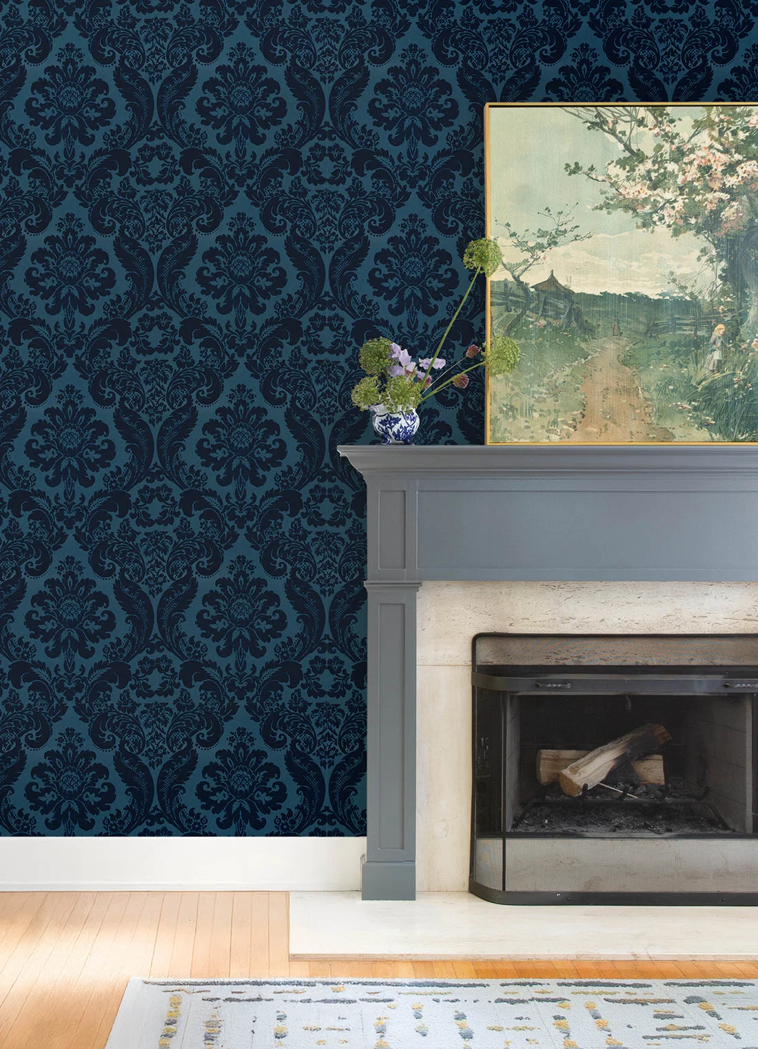 Deep blue damask wallpaper beside a gray fireplace surround